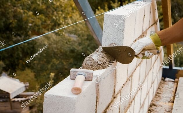 stock-photo-a-skilled-worker-builds-a-solid-wall-using-concrete-bricks-at-a-construction-site-for-a-new-home-2746738643 — kopia — kopia